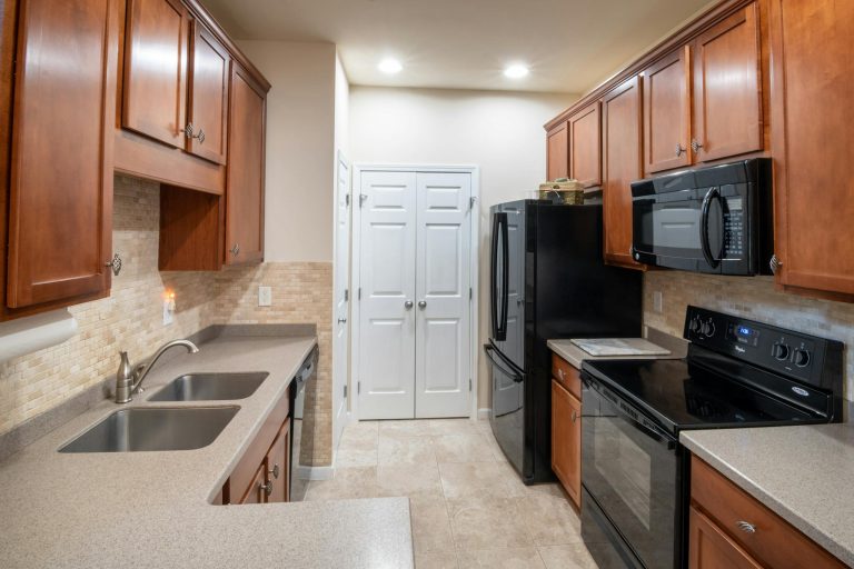 Spacious modern kitchen with wood cabinets, sleek countertops, and stainless steel appliances.